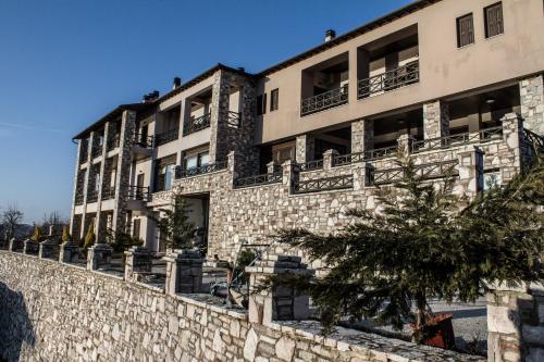 an apartment building with balconies on a stone wall at Titagion Hotel in Plastiras