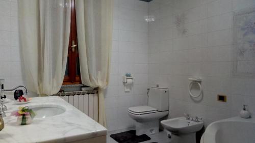 a white bathroom with a toilet and a sink at Villa Berra - Via Postale 63/A in Berra