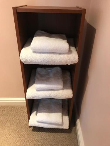 Baño con 4 toallas en un estante de madera para toallas en The Cottage, cosy 2 bedroom pet friendly perfect for contractors free secure parking,CCTV, en Leeds