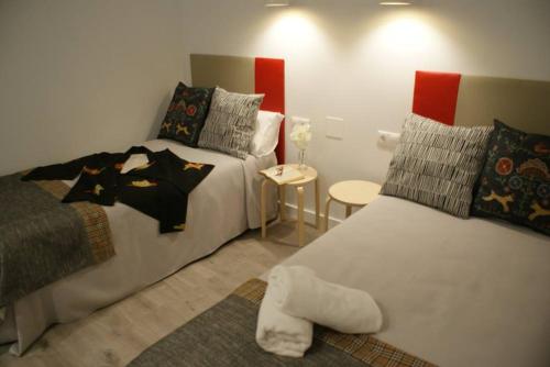 a bedroom with two beds and a table with a stool at Apartamentos La Estación M&S in Albacete