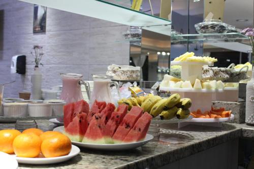 a buffet with fruit on plates on a counter at AJ Hotel Chapecó - Fácil Acesso Pátio Shopping e Rótula da Bandeira in Chapecó