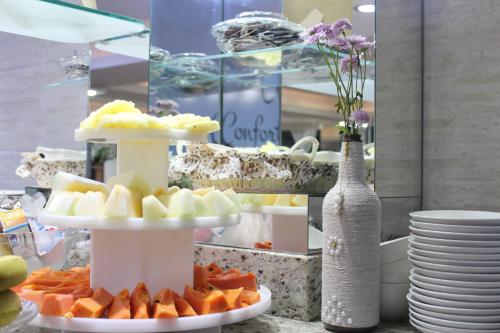 a table with two tiers of fruit on plates at AJ Hotel Chapecó - Fácil Acesso Pátio Shopping e Rótula da Bandeira in Chapecó