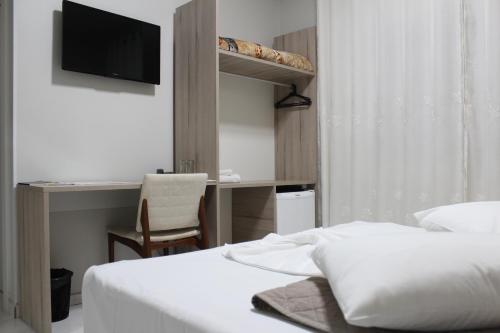 a bedroom with a bed and a desk with a television at AJ Hotel Chapecó - Fácil Acesso Pátio Shopping e Rótula da Bandeira in Chapecó