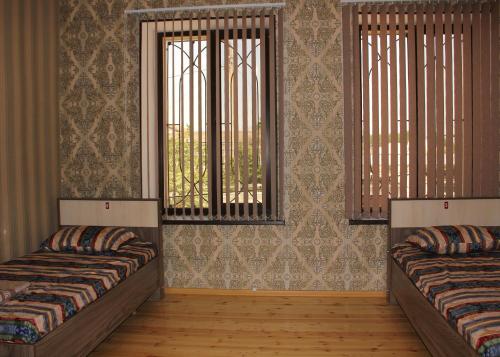 a room with two beds and two windows at VM Hostel in Ganja