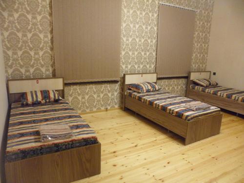 two beds in a room with wooden floors at VM Hostel in Ganja