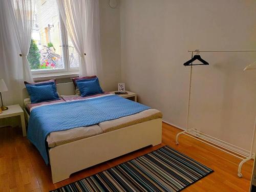 Schlafzimmer mit einem Bett mit blauer Bettwäsche und einem Fenster in der Unterkunft Spacious apartment DIANA in Helsinki city center in Helsinki