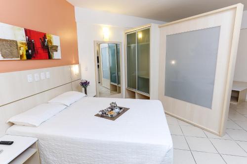 a bedroom with a white bed and a large window at Hotel Metropolitan Canoas - 4,1 km do Terminal Embarque Aéreo ParkShopping Canoas in Canoas