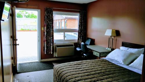 1 dormitorio con cama, ventana y escritorio en Kings Inn Midland, en Midland