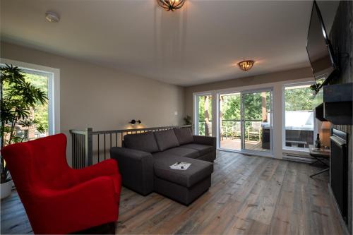a living room with a couch and a red chair at Les Chalets Sauvignon in Mont-Tremblant