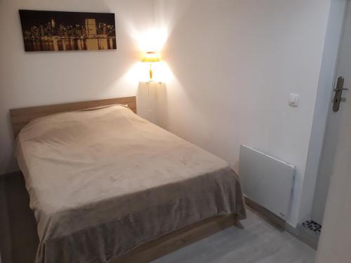 um pequeno quarto com uma cama e um candeeiro em Appartement À Valence em Valence