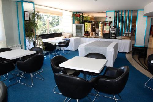 バラックヴィルにあるauthentic by balladins – Rodez / Le Ségalaの白いテーブルと黒い椅子が備わるレストラン