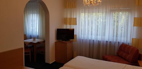 a room with a bed and a tv and a chair at Hotel Beuss in Oberursel