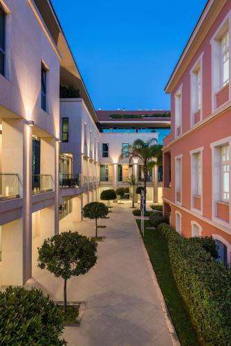 a walkway between two buildings with trees in a courtyard at Trianon Luxury Apartments & Suites in Chania Town