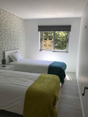 ポボア・デ・バルジンにあるCalua apartment in Povoa de Varzimのベッドルーム1室(ベッド2台、窓付)