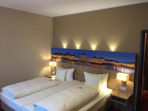 a bedroom with a large white bed with a painting on the wall at Parkhotel Leiser in Planegg