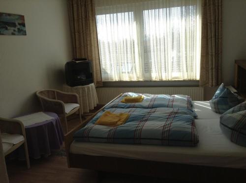 a bedroom with a bed and a tv and a window at Hotel Rotbuche in Westoverledingen