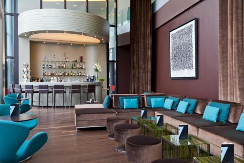 un hall avec des chaises bleues et un bar dans l'établissement Hôtel Barrière Lille, à Lille