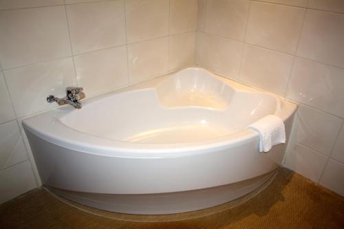 a white bath tub in a bathroom with a sink at authentic by balladins – Rodez / Le Ségala in Baraqueville