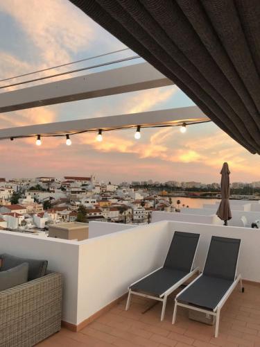 a balcony with two chairs and a view of a city at Casa Kiki in Ferragudo