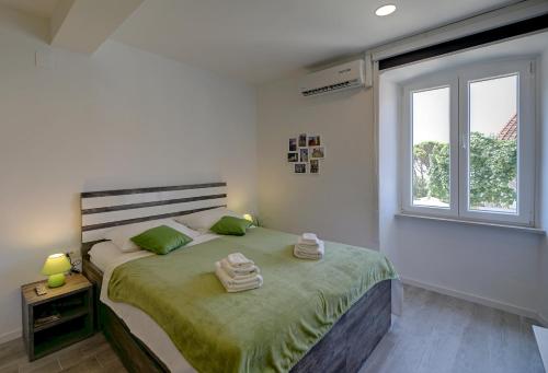 um quarto com uma cama com lençóis verdes e uma janela em Timeless City Center Apartments em Dubrovnik