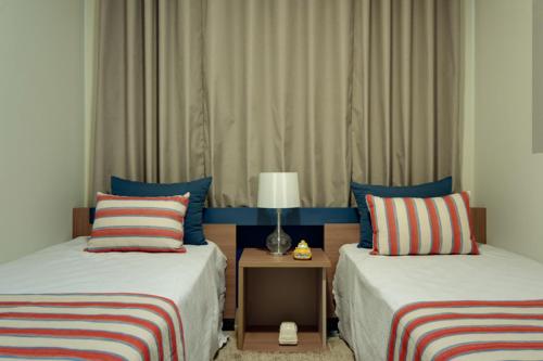 une chambre avec deux lits et une table avec une lampe dans l'établissement Alta Vista Thermas Resort, à Caldas Novas