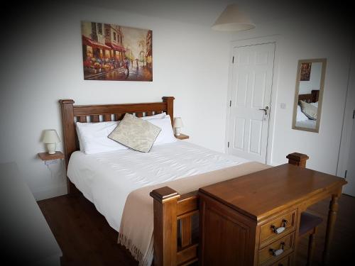1 dormitorio con cama y mesa de madera en Mulranny House, en Mulranny
