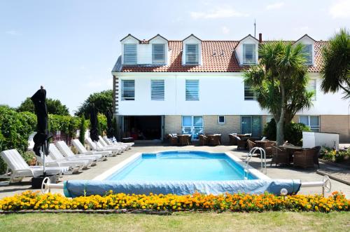 a swimming pool in front of a house with lounge chairs at Beachcombers Hotel in Saint Helier Jersey