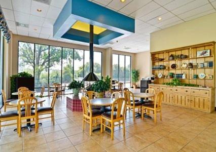 a dining room with tables and chairs and a kitchen at Days Inn by Wyndham St George in Saint George