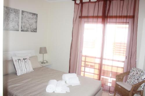 sypialnia z łóżkiem, krzesłem i oknem w obiekcie Cabanas1 w mieście Cabanas de Tavira