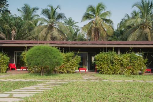 a building with red benches and palm trees at Hotel Coucoue Lodge in Assinie