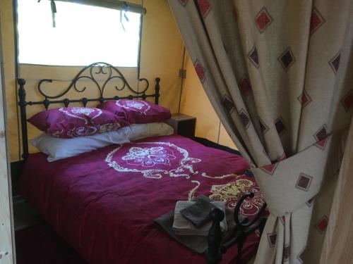 sypialnia z łóżkiem z fioletową pościelą i oknem w obiekcie Lincolnshire Glamping w mieście Horncastle