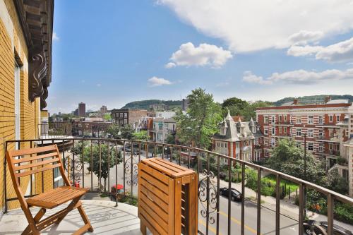 a balcony with a wooden chair and a view of a city at Les Lofts du Plateau in Montreal
