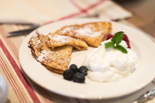 a plate of pancakes with whipped cream and berries at The Woodstocker B&B in Woodstock