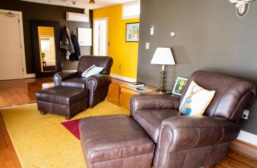 a living room with a leather couch and two chairs at The Woodstocker B&B in Woodstock