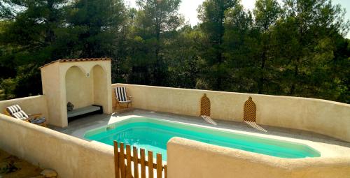 a swimming pool in a backyard with two chairs at Granja Masia Katmandu in Cretas