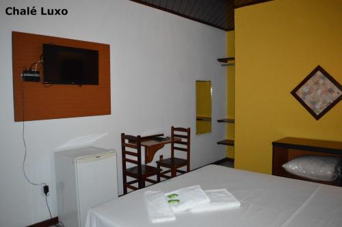 a room with a table and a tv on the wall at Pousada Lapônia in Penedo