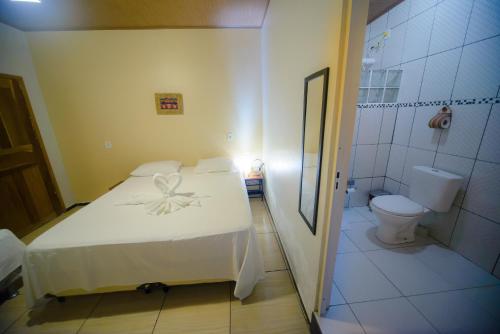 1 dormitorio con cama blanca y aseo en Pousada São José, en Barreirinhas
