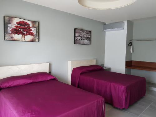 two beds in a room with purple sheets at Hotel Boutique La Toja Campeche in Campeche