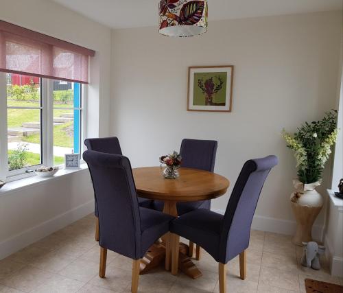 uma sala de jantar com uma mesa de madeira e cadeiras azuis em Olavat Cottage detached property with parking em Inverness