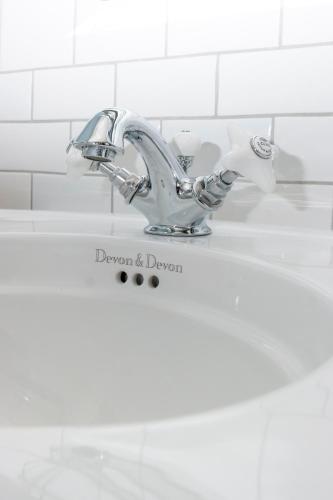 a white bathroom sink with a chrome faucet at Historisches Bauernhaus Fehmarn in Strukkamp auf Fehmarn