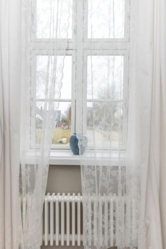 a window with white curtains and a radiator at Historisches Bauernhaus Fehmarn in Strukkamp auf Fehmarn