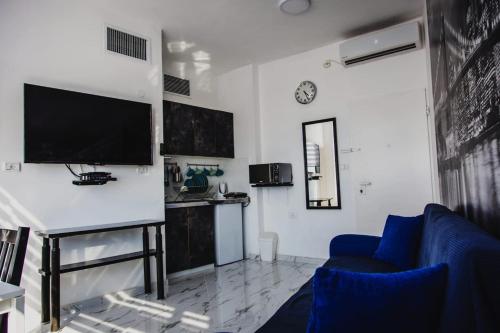 uma sala de estar com uma televisão e uma cadeira azul em Ashdod Beach Hotel em Ashdod