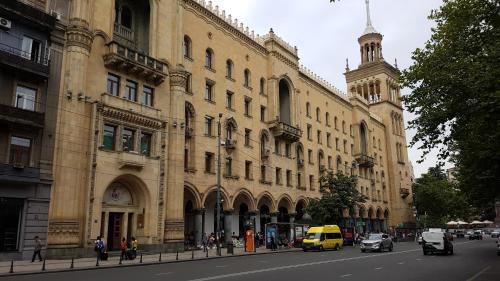 a yellow van driving down a street in front of a building at Sweet Rooms Inn in Tbilisi City