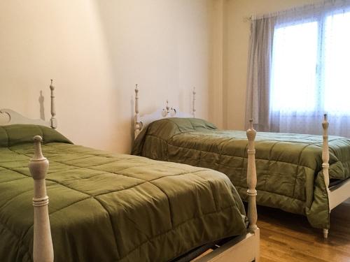 2 camas individuales en un dormitorio con ventana en Departamento Temporario Bahia Blanca en Bahía Blanca