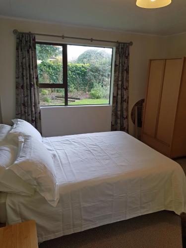 a bedroom with a large bed with a large window at Garden Retreat in Otaki