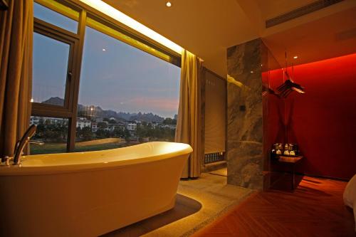 张家界Riverside Peak Lodge Zhangjiajie Wulingyuan National Park的带浴缸和大窗户的浴室