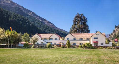 a house in a field with mountains in the background at Bella Vista Queenstown in Queenstown