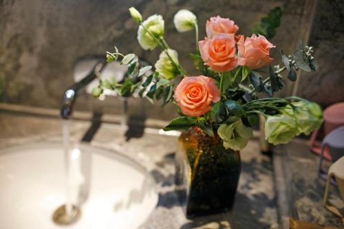 a vase of flowers sitting next to a sink at Riverside Peak Lodge Zhangjiajie Wulingyuan National Park in Zhangjiajie