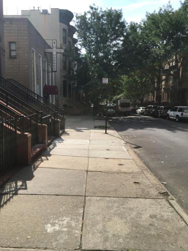 a city street with a sidewalk and a street sign at NYC Townhouse Apartment in New York