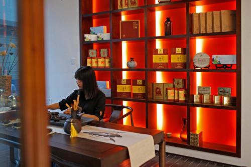 a woman sitting at a table in front of a book shelf at Riverside Peak Lodge Zhangjiajie Wulingyuan National Park in Zhangjiajie